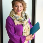 Woman Smiling and Holding Teal Book